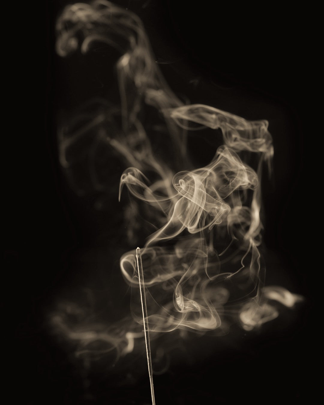 Pale incense smoke curling against a black background