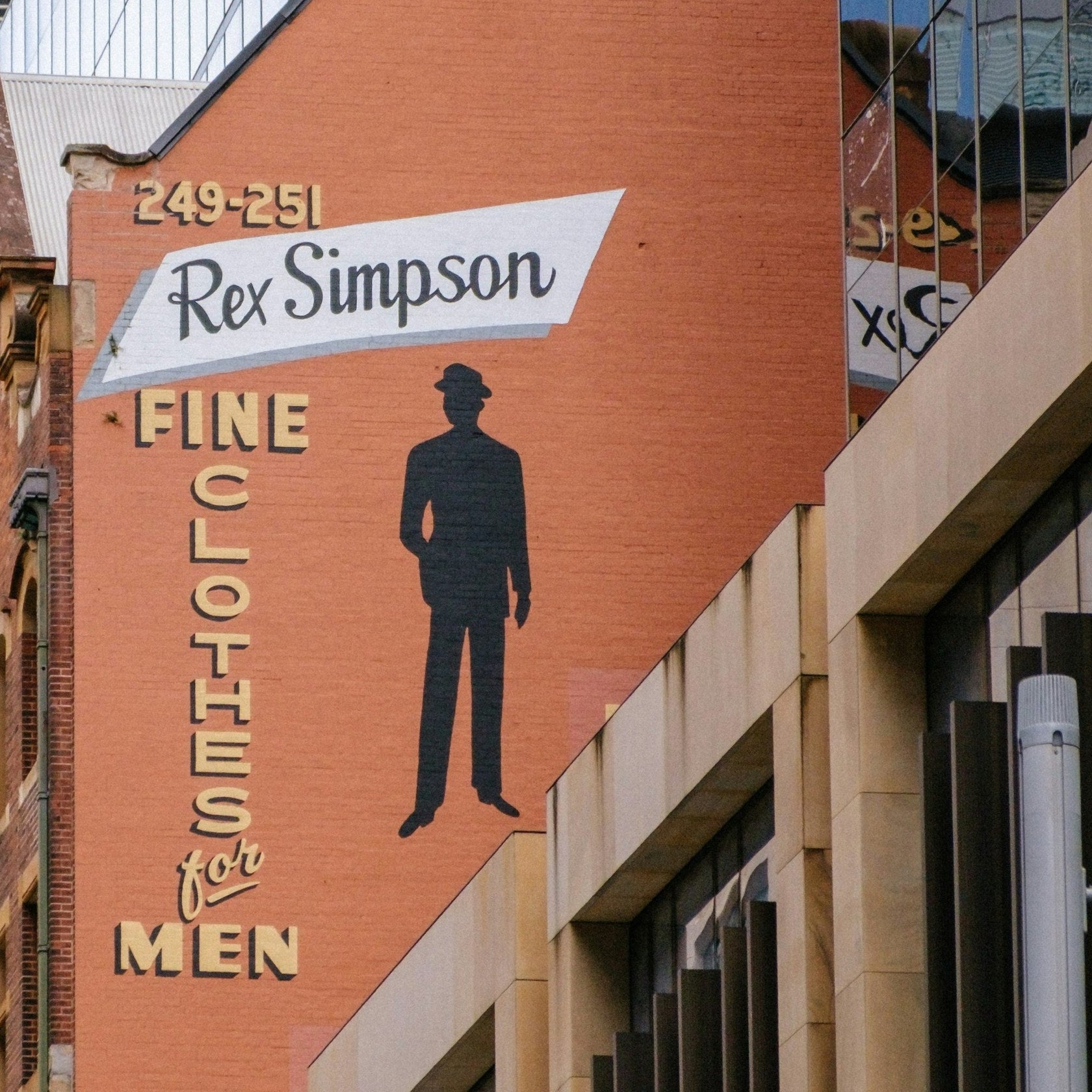 A brick gable in Surry Hills, Sydney, painted with a vintage menswear sign, the inspiration for LUMIRA No352 Leather and Cedar