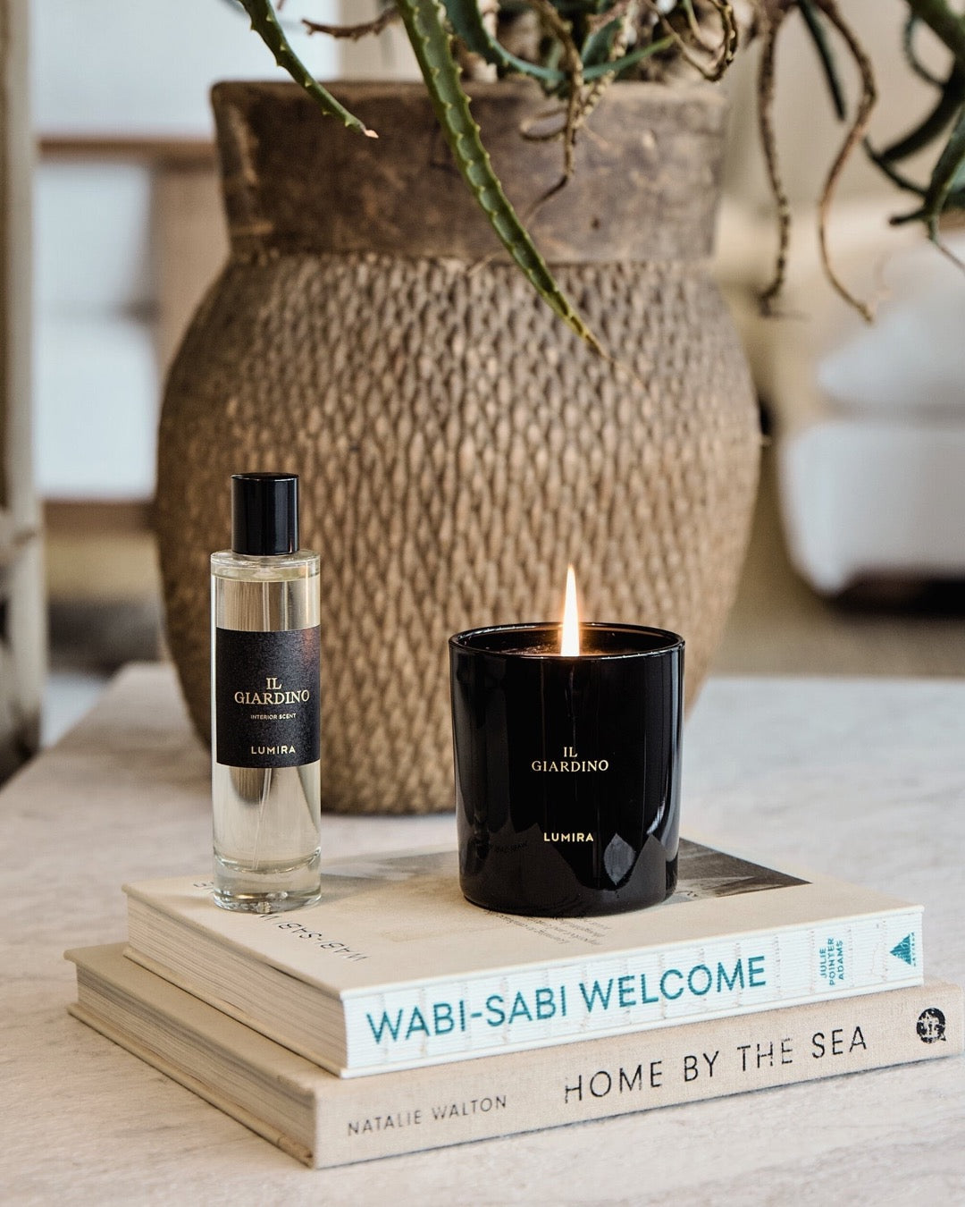 The LUMIRA Il Giardino candle and room spray on a stack of books