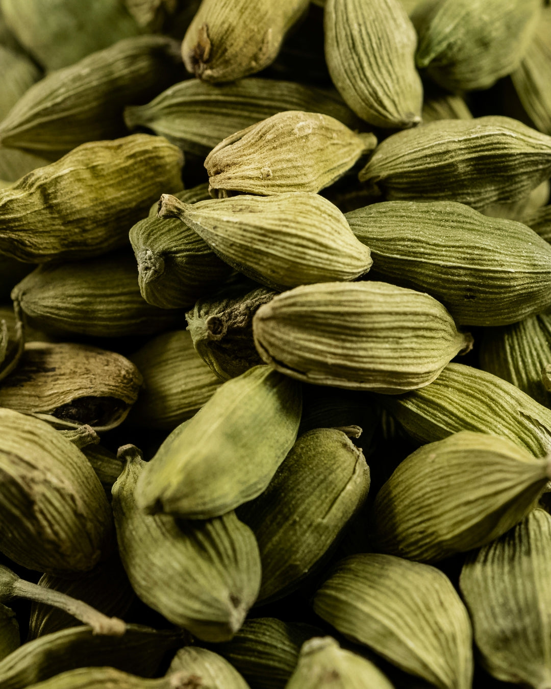 A pile of pale green cardamom pods